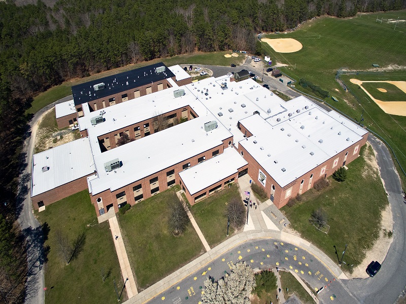 an aerial view of a school with a baseball field in the background