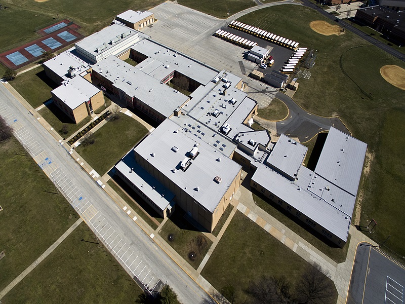 an aerial view of a school with a white metal roof