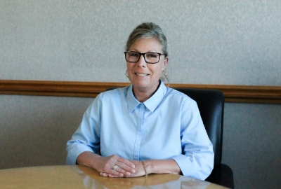 a woman wearing glasses and a blue shirt sits at a table