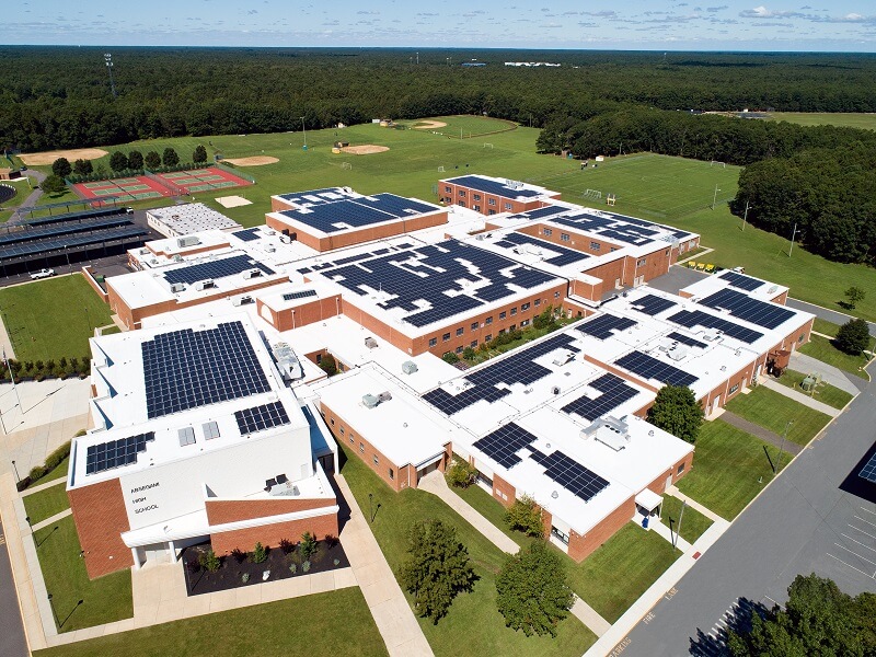 an aerial view of a complex brick school building with solar panels on the roof