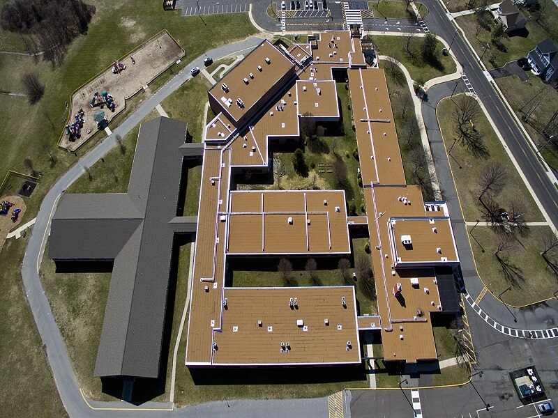 an aerial view of a large brown building with several roofs