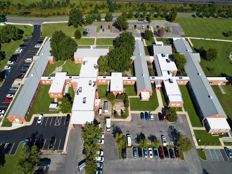 an aerial view of a large building with a parking lot in front of it with several cars