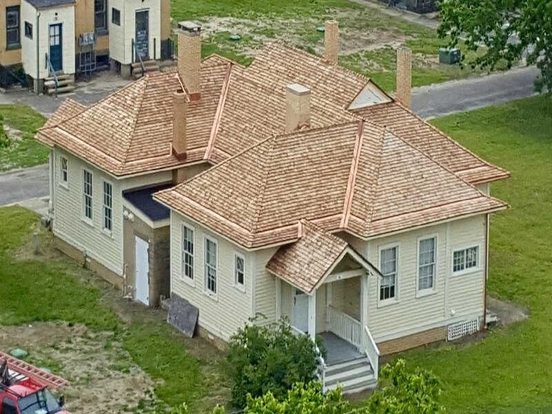 an aerial view of a pale yellow house with a copper roof