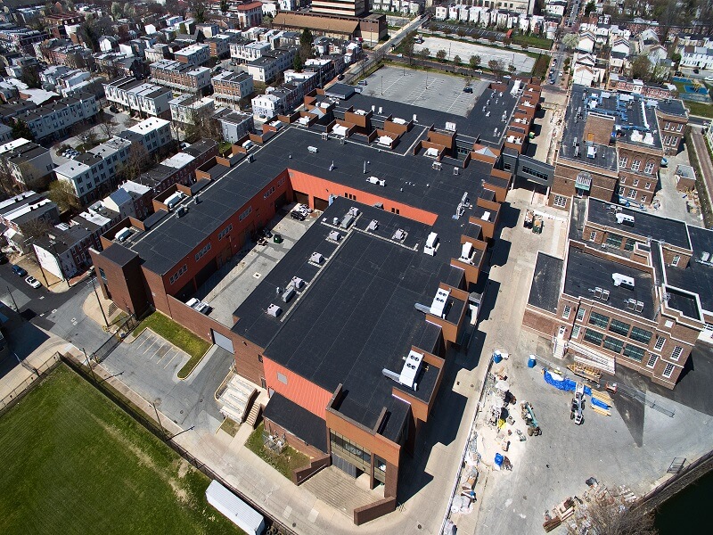 an aerial view of a large building with a black roof surrounded by other buildings in a city
