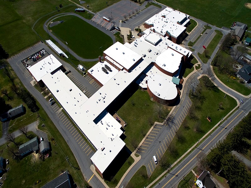 an aerial view of a large high school with white roofs
