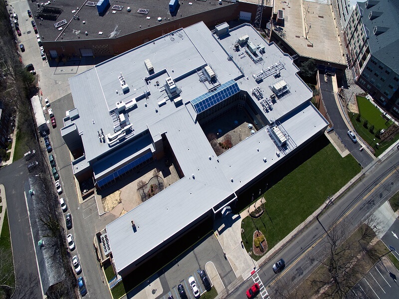 an aerial view of a large building with a white roof surrounded by two other buildings