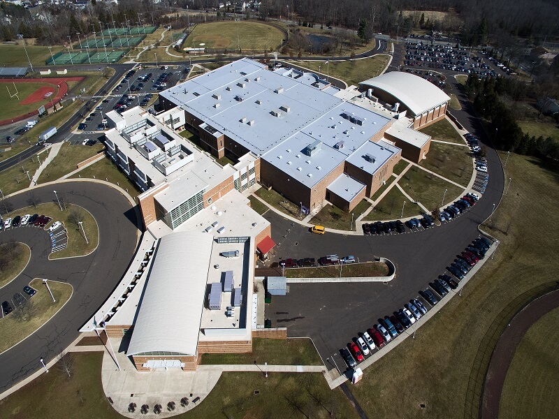 an aerial view of a large high school building with a white roof