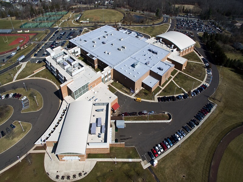 an aerial view of a large high school building with a white roof