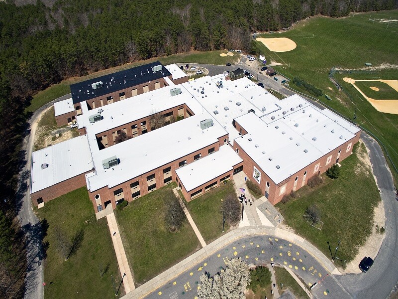 an aerial view of a large brick building with a white roof
