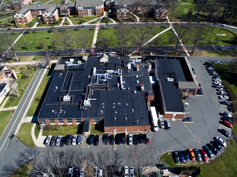 an aerial view of a large building with a black roof surrounded by cars in a parking lot